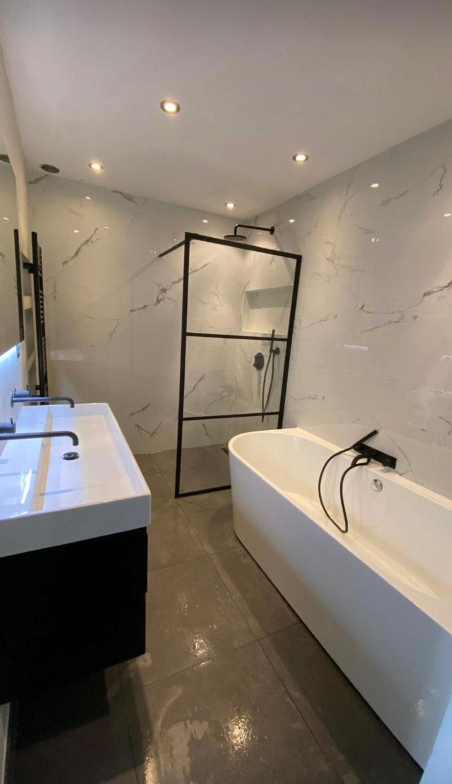 Badkamer in marmerlook met ligbad en inloopdouche