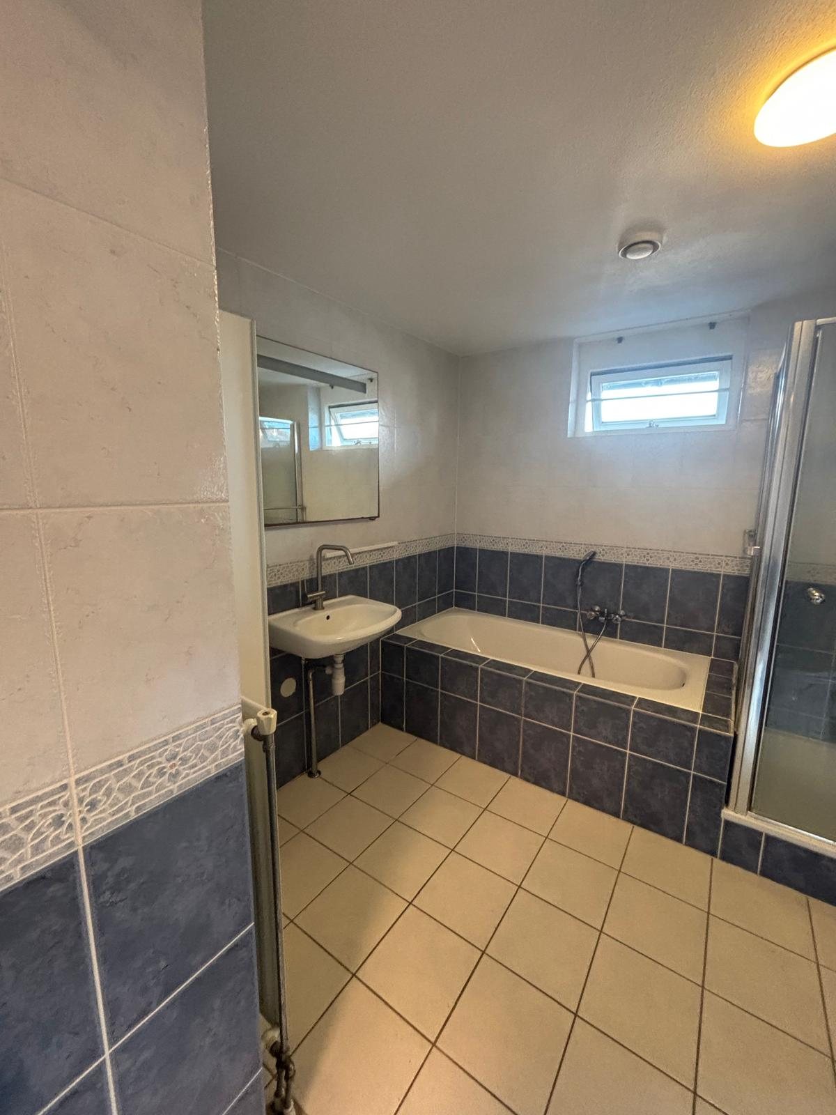 Oude badkamer met blauwe tegels voor de renovatie
